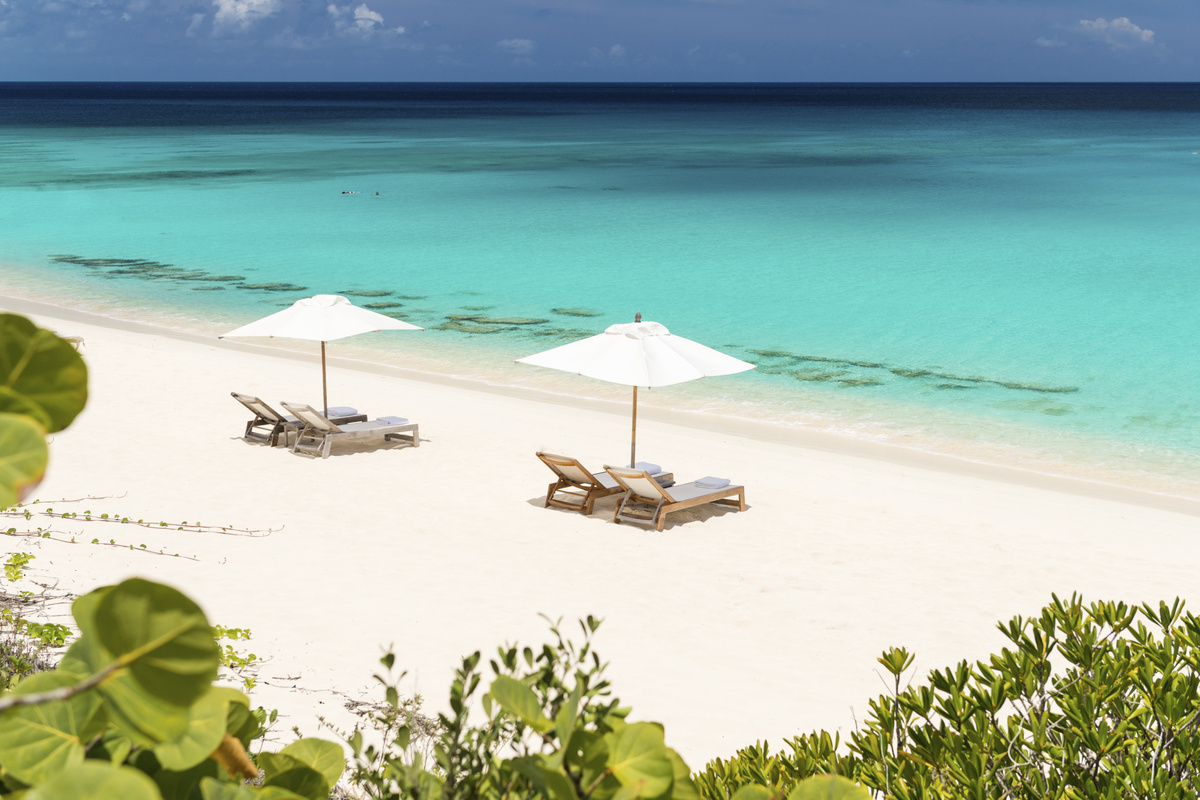 Two pairs of loungers on an empty white-sand beach