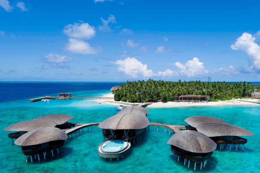 Shell-roofed overwater villas on a turquoise reef