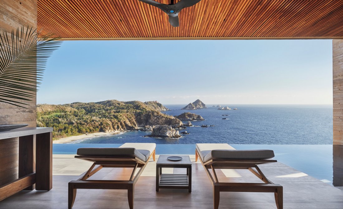 An open-air terrace and infinity pool above a rocky Pacific cove